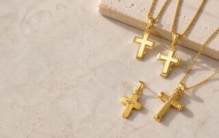 14K gold chains with classic gold cross pendants on a marble surface.